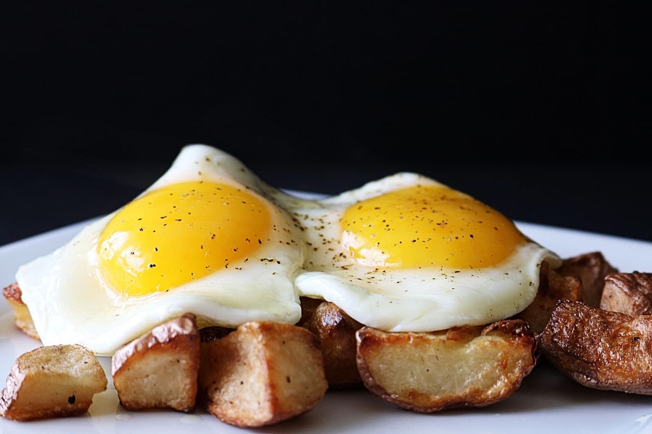 Two fried eggs with sausage and roast potatoes
