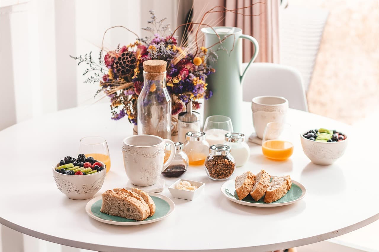 A bright brunch table with pastries, fruit and coffee