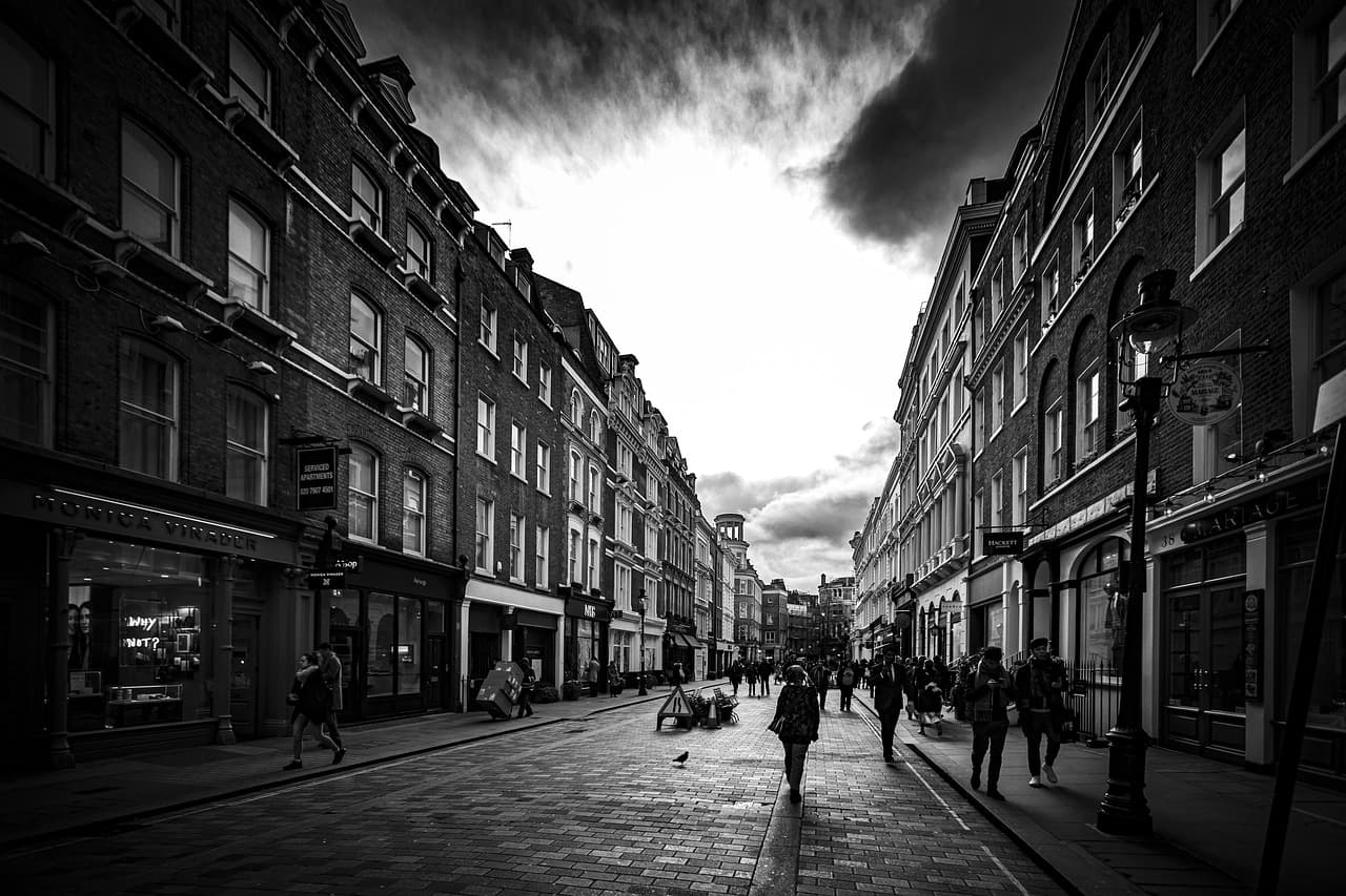 People walking down a city street between tall old buildings